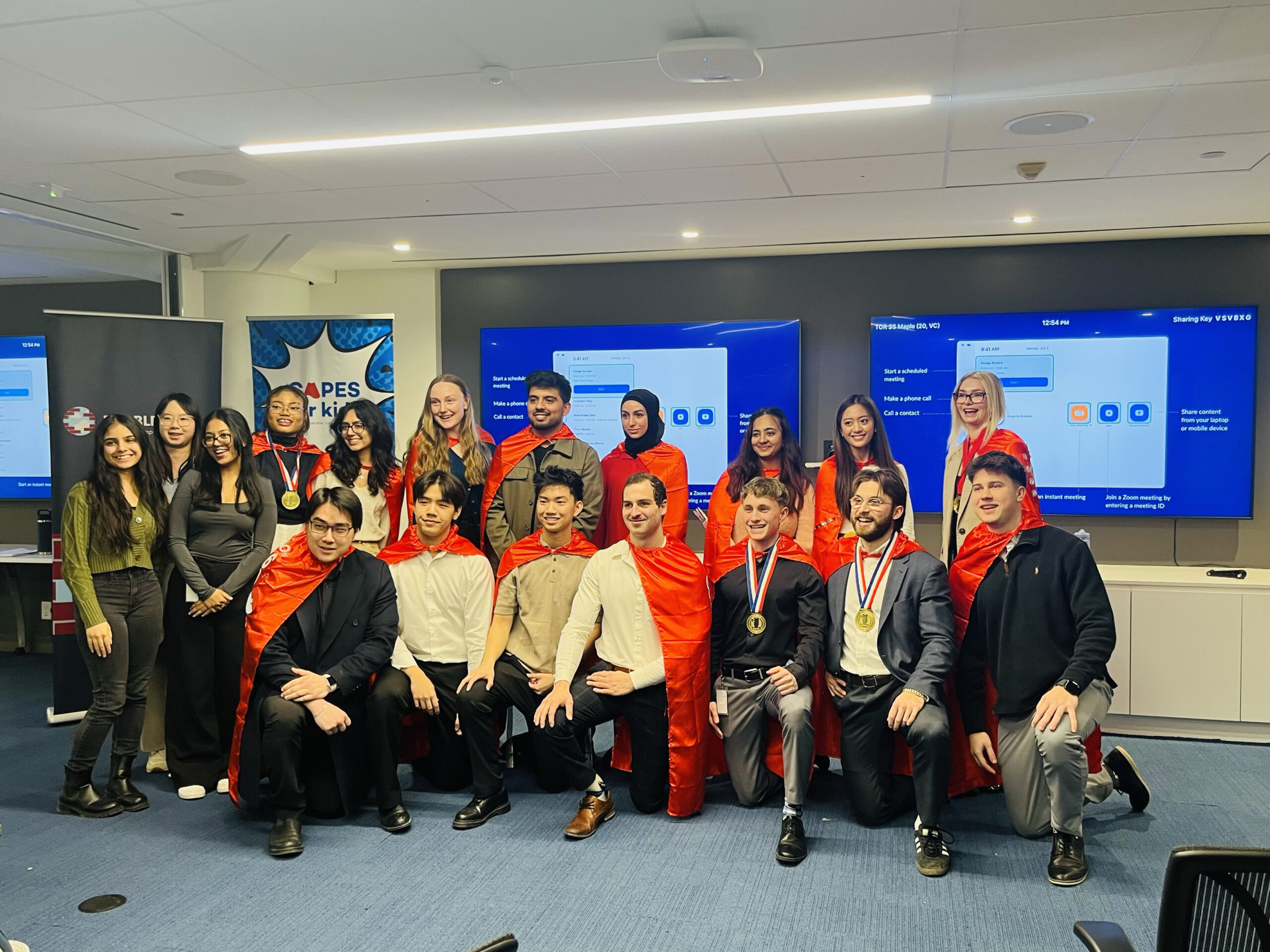 A group of coworkers wearing red capes in an office