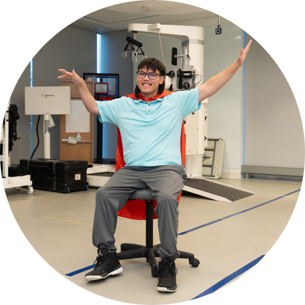 A teenage boy wears a red cape and strikes a superhero pose