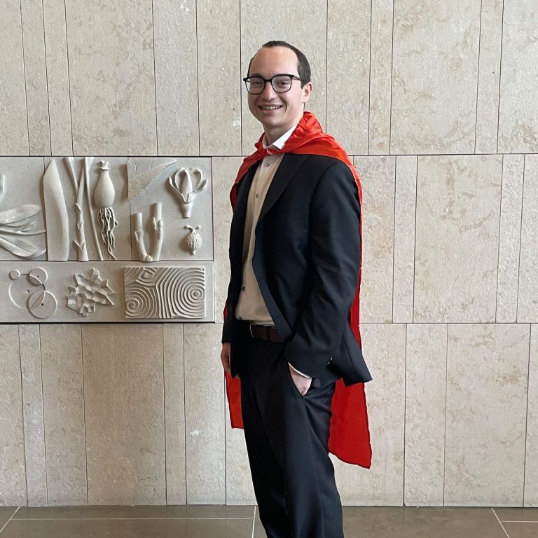 An adult wearing a suit and red cape