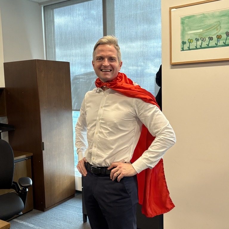 An adult wearing a red cape